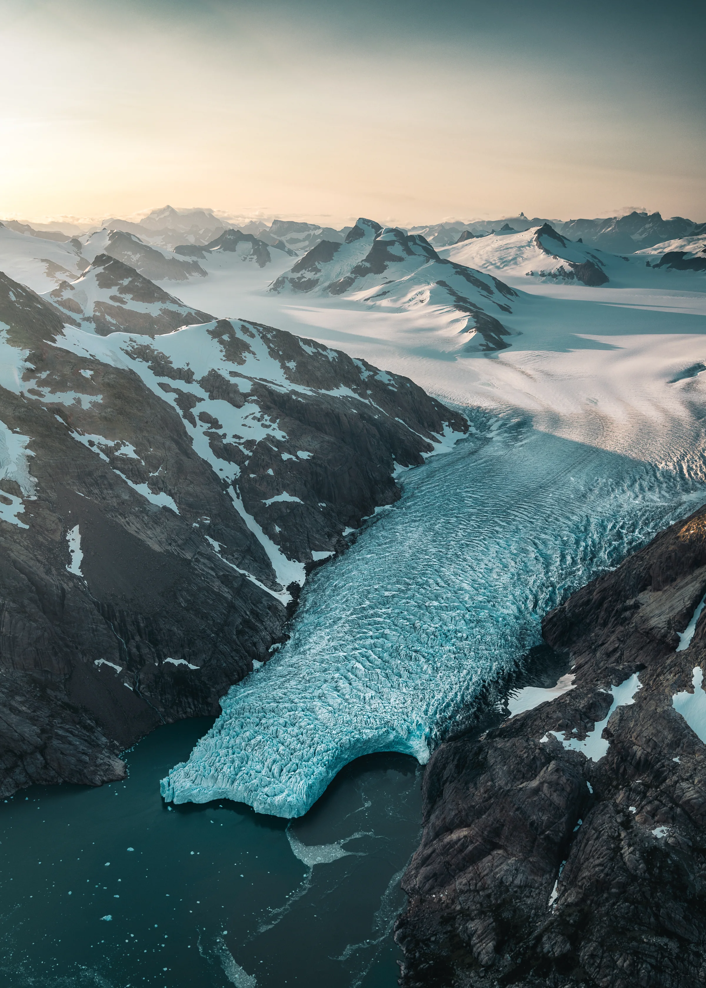 A glacier flowing through Arctic mountains into the sea