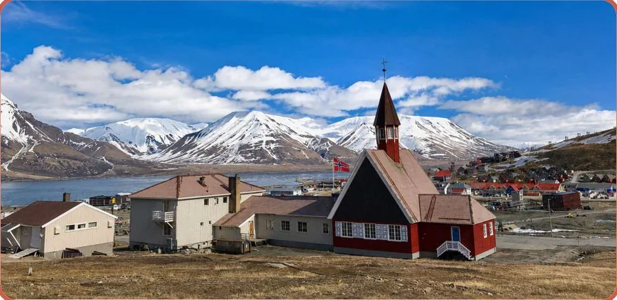 Svalbard church with snow-capped mountains behind