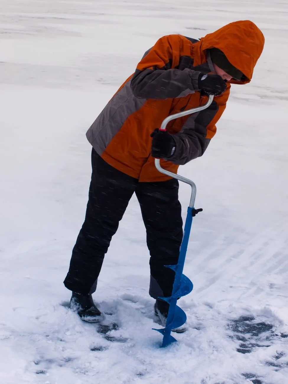 Researcher drilling into Arctic ice with a hand auger