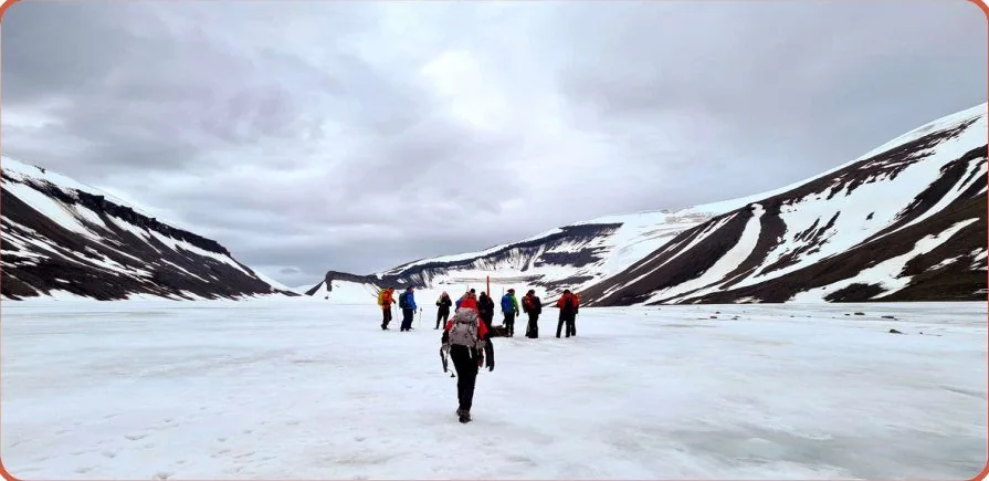 A group crossing a glacier with a guide during fieldwork in Svalbard